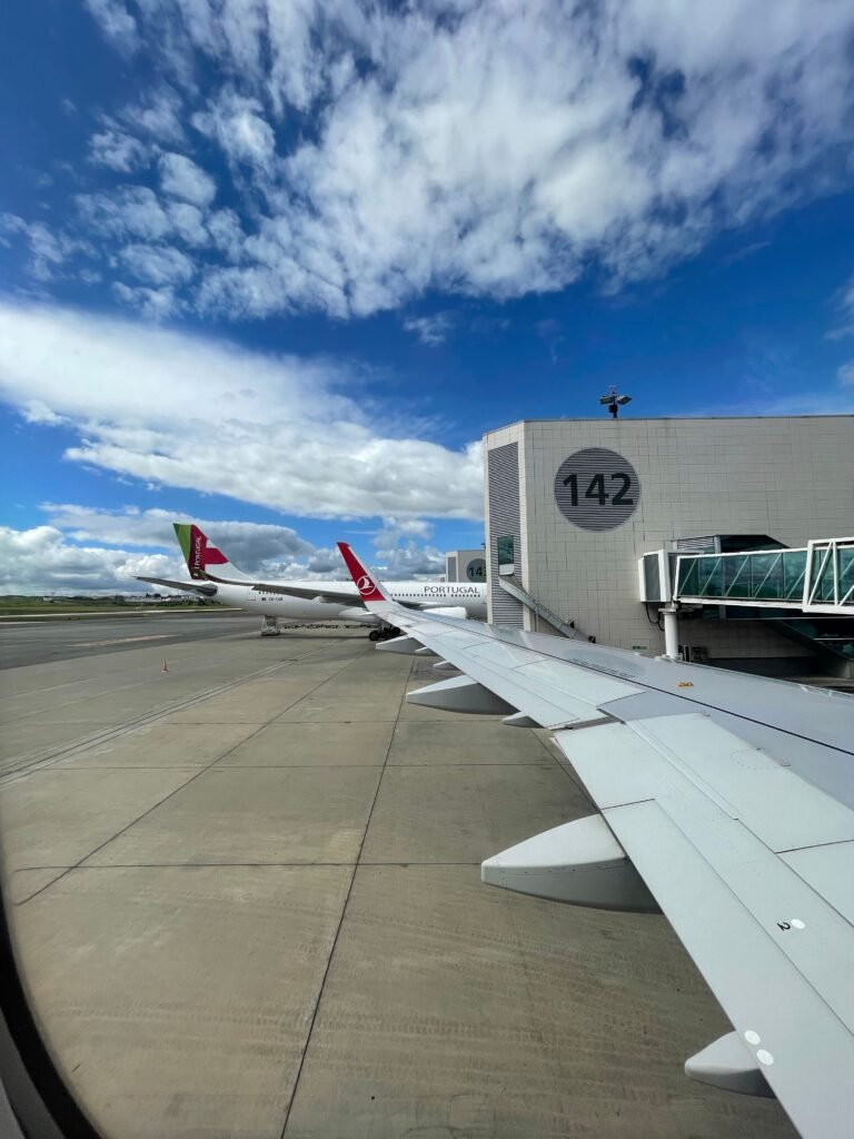 Airplane wing view at the airport gate, clear blue sky above. Ideal for travel and aviation themes.